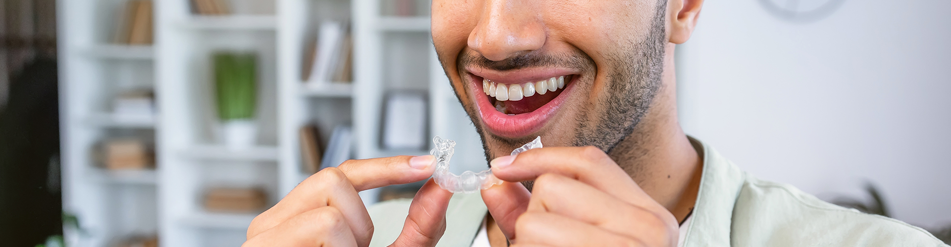 smiling man holding clear aligner