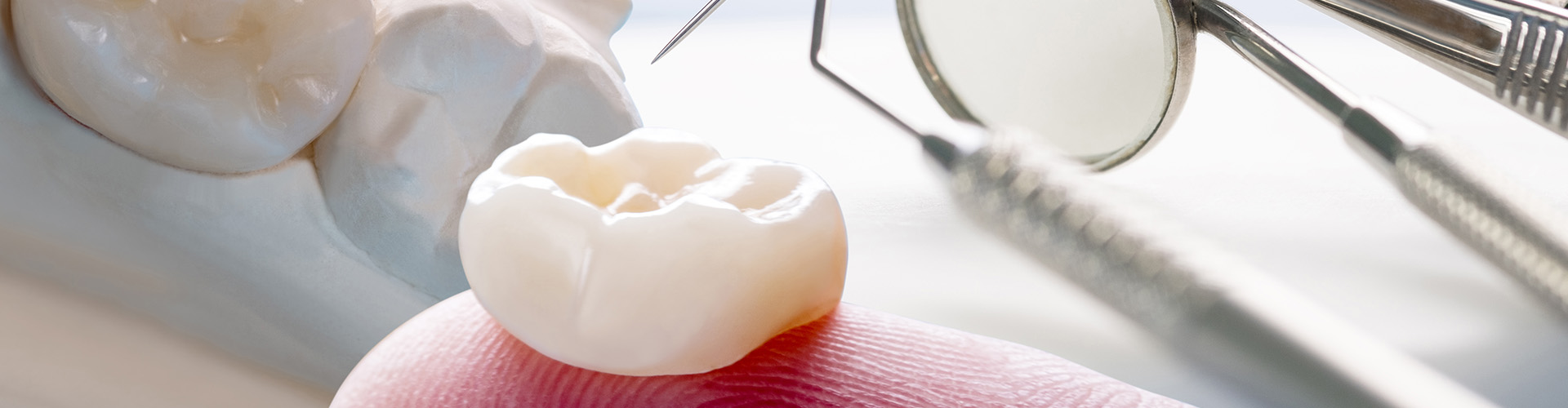 dental crown on finger with dental tools and mouth model