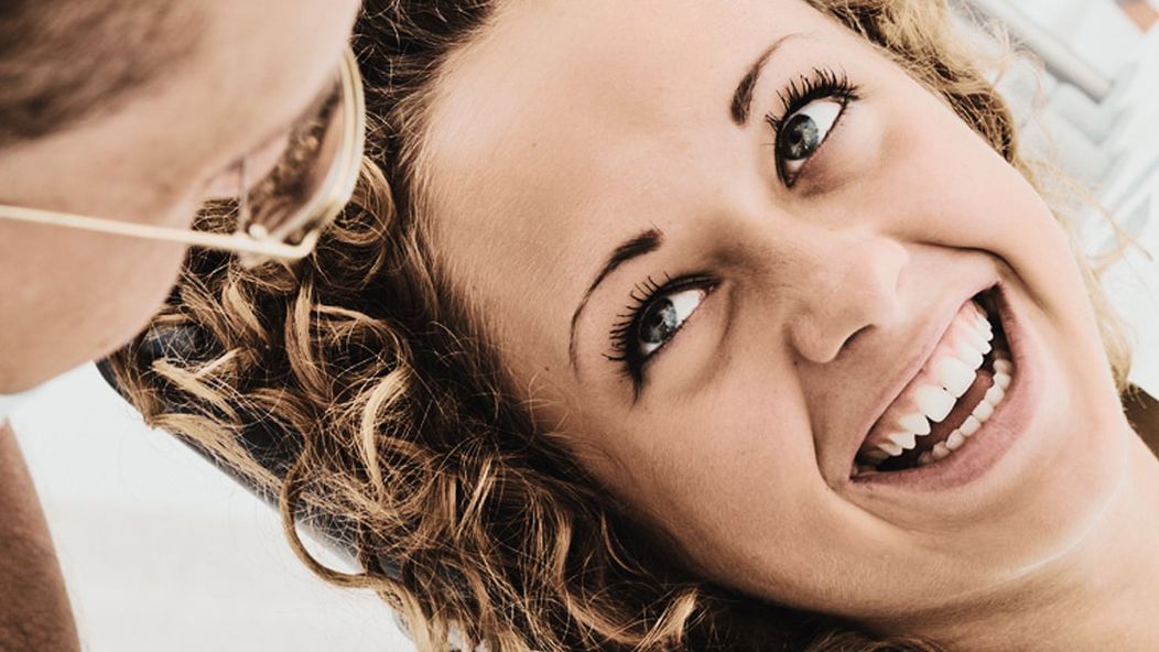 An image of a smiling woman looking up at a dentist