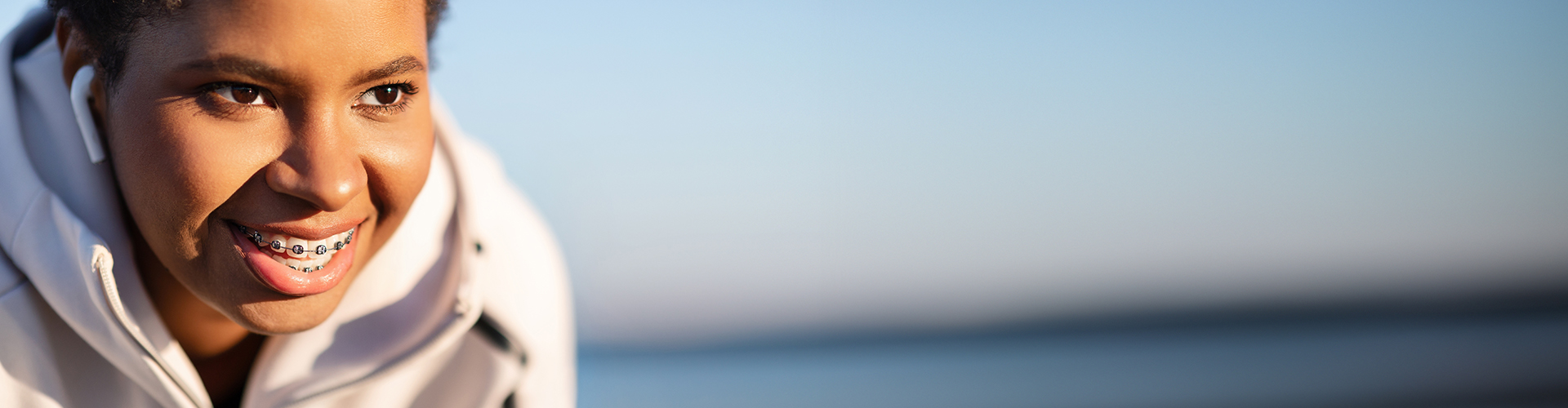 smiling woman with braces wearing earpods