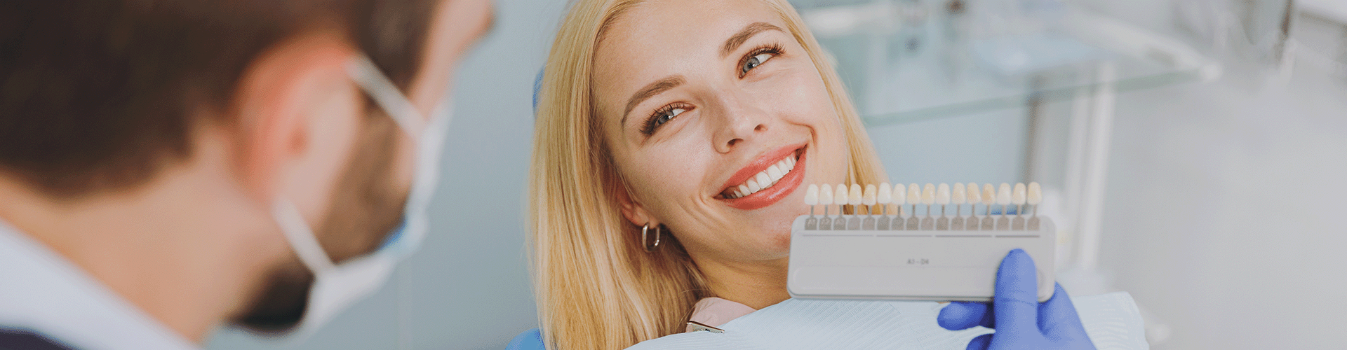 dentist holding shade-matcher next to patient's teeth