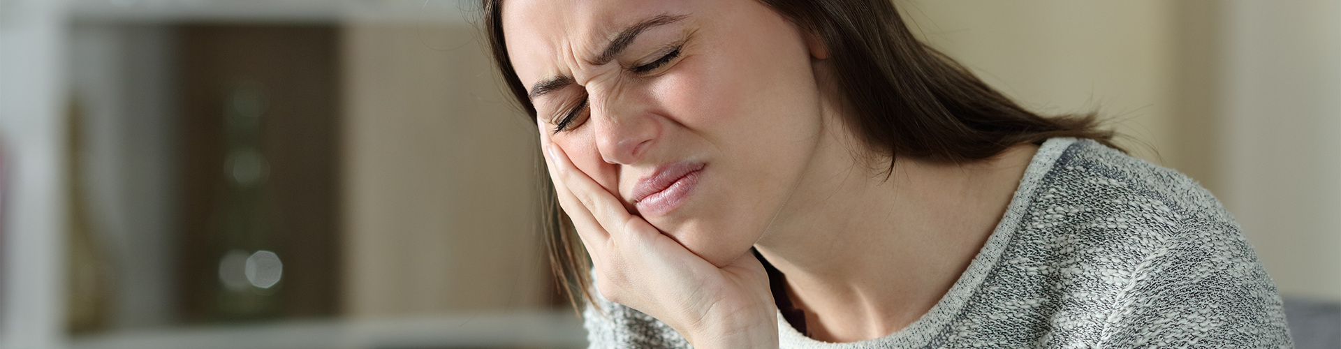 female holding jaw in pain